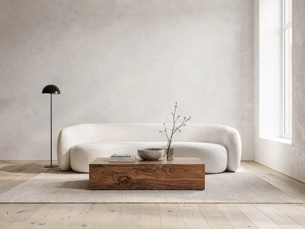 A living room with a curved sofa in front of a pale plaster wall: Ivory bouclé