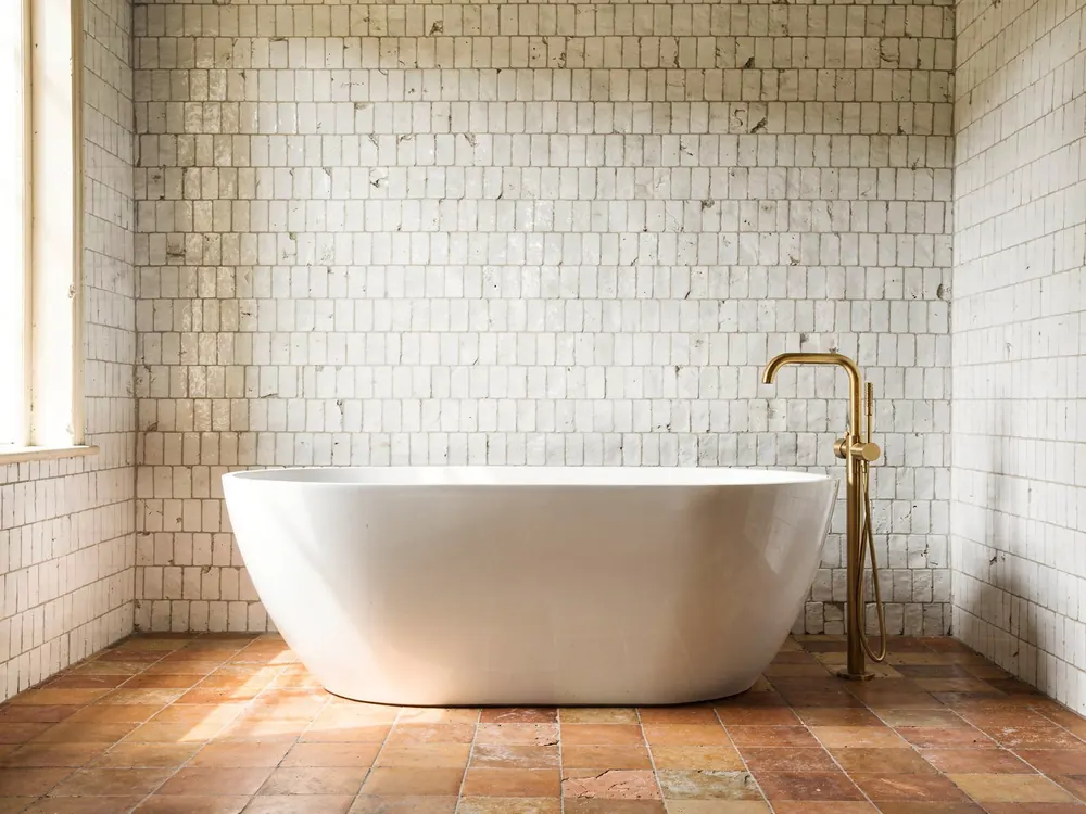 A bathroom with its terracotta floor replaced by black and white cement tiles, the walls unchanged, before