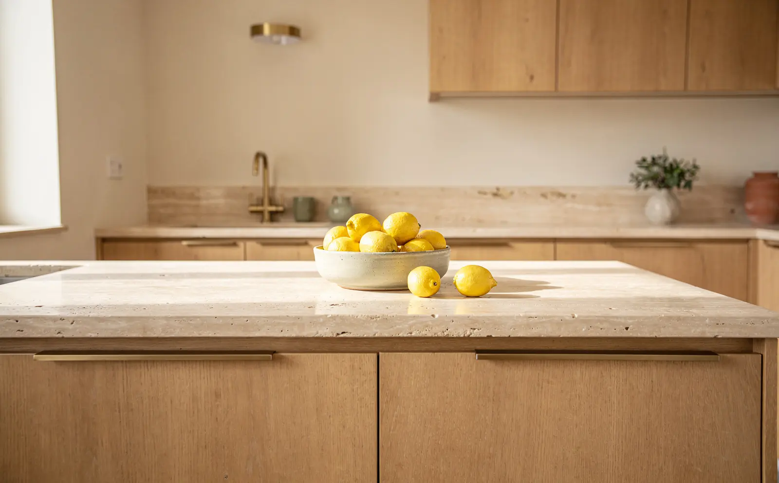 A kitchen with a travertine counter and oak cabinets