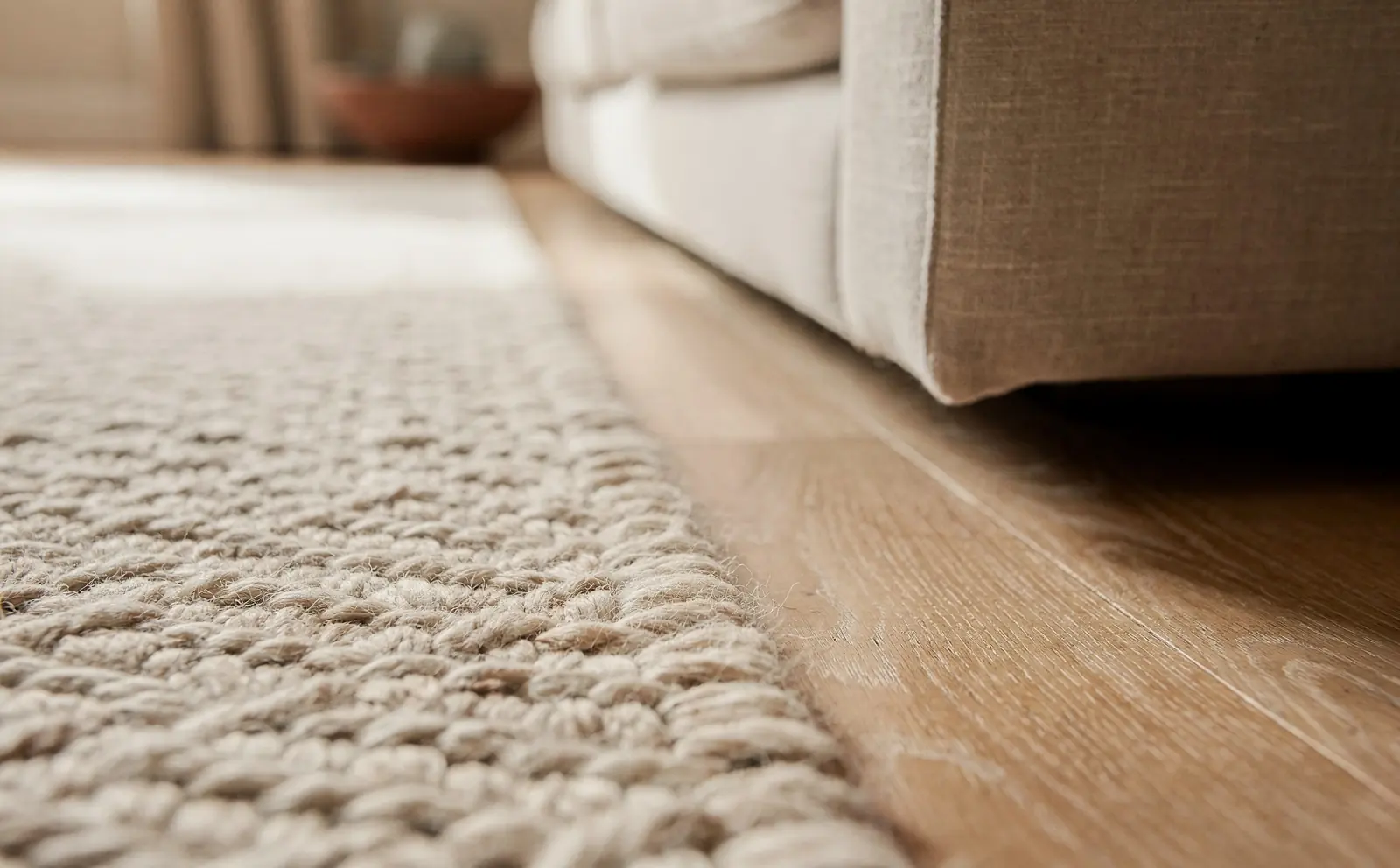 A thick wool rug on an oak floor beside a linen sofa