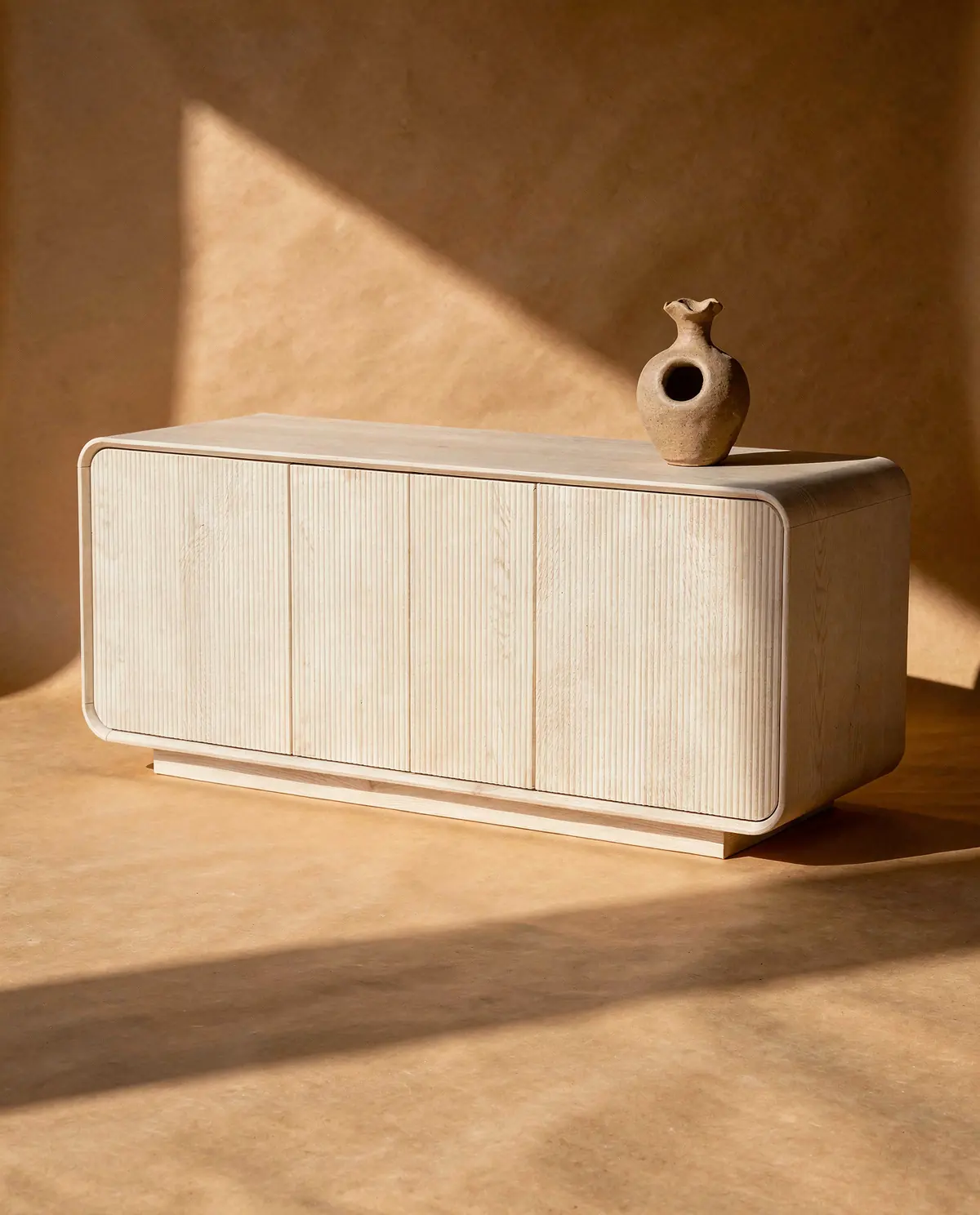 The Alma sideboard alone on a sand paper backdrop with a beam of sunlight, a studio cover shot